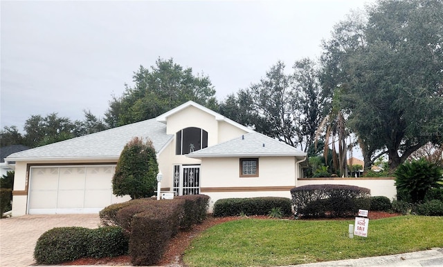 view of front of property with a garage, a shingled roof, driveway, stucco siding, and a front lawn