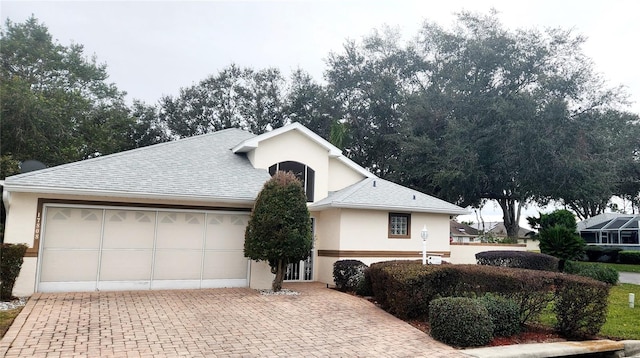 view of front of home featuring a garage, roof with shingles, decorative driveway, and stucco siding