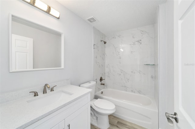 full bathroom with tiled shower / bath, toilet, wood-type flooring, vanity, and a textured ceiling