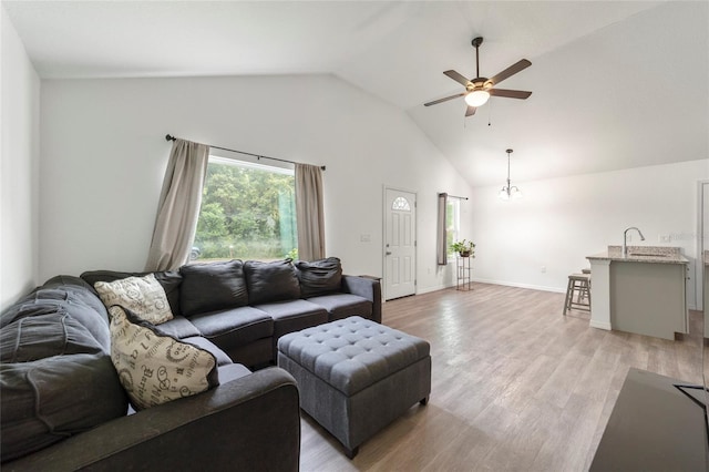 living room with light wood-type flooring, ceiling fan, sink, and vaulted ceiling