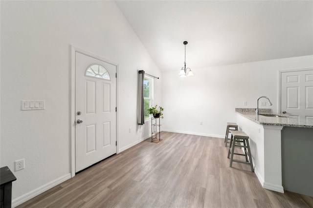 entryway featuring an inviting chandelier, lofted ceiling, light hardwood / wood-style flooring, and sink