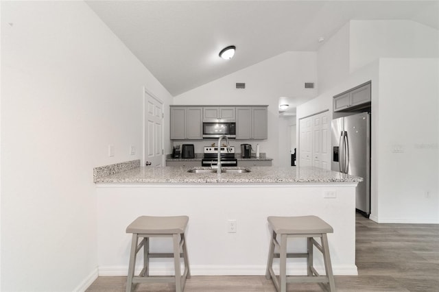 kitchen featuring a kitchen bar, kitchen peninsula, sink, and appliances with stainless steel finishes