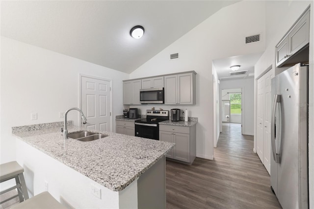 kitchen featuring a kitchen breakfast bar, dark hardwood / wood-style flooring, appliances with stainless steel finishes, kitchen peninsula, and sink