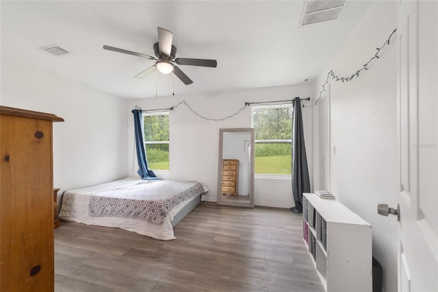 bedroom with multiple windows, hardwood / wood-style flooring, and ceiling fan