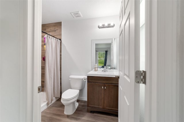 bathroom with hardwood / wood-style floors, a shower with curtain, toilet, and vanity