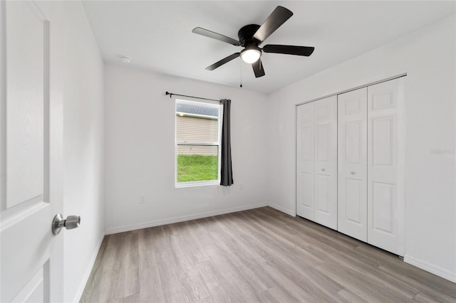 unfurnished bedroom with light wood-type flooring, ceiling fan, and a closet