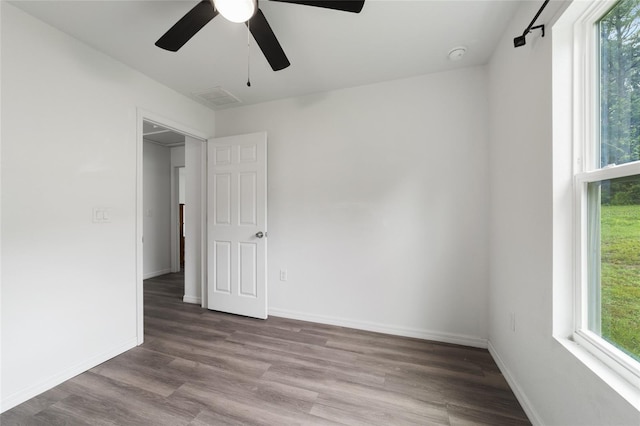 empty room featuring ceiling fan, plenty of natural light, and wood-type flooring