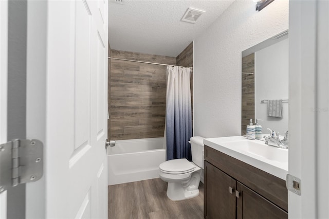 full bathroom with toilet, hardwood / wood-style floors, vanity, a textured ceiling, and shower / bath combo with shower curtain