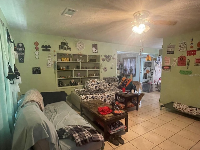 living room with ceiling fan, a textured ceiling, and light tile patterned floors