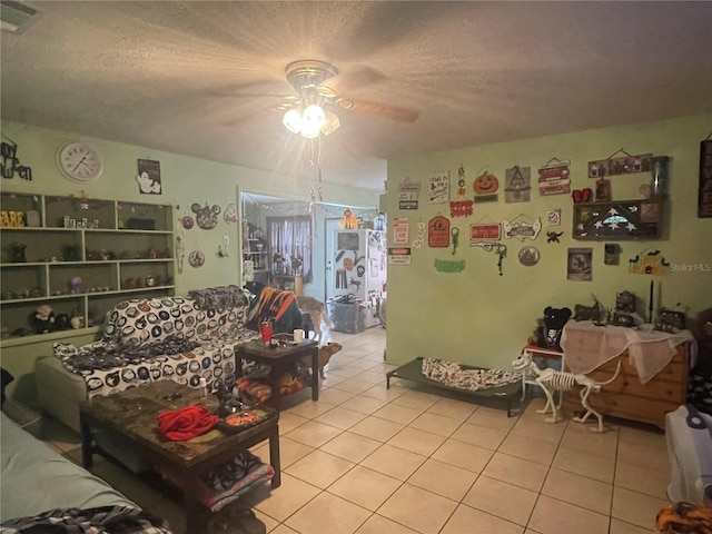 living room with ceiling fan, light tile patterned floors, and a textured ceiling