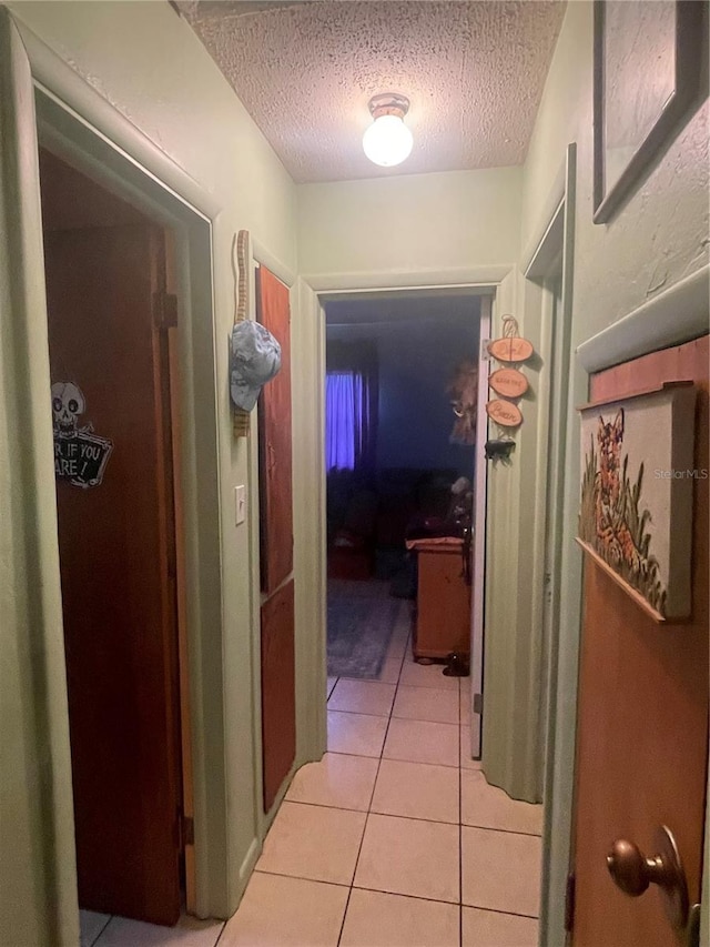 hall with light tile patterned floors and a textured ceiling