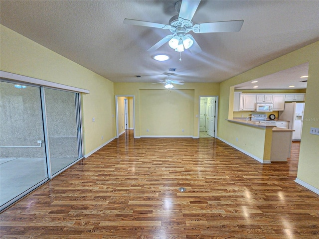 unfurnished living room featuring ceiling fan, hardwood / wood-style flooring, and a textured ceiling