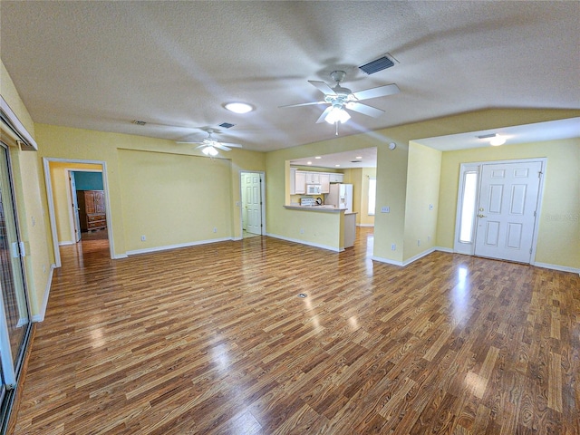 unfurnished living room featuring a textured ceiling, lofted ceiling, dark hardwood / wood-style floors, and ceiling fan