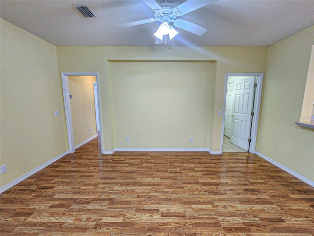 empty room featuring ceiling fan, hardwood / wood-style flooring, and a textured ceiling