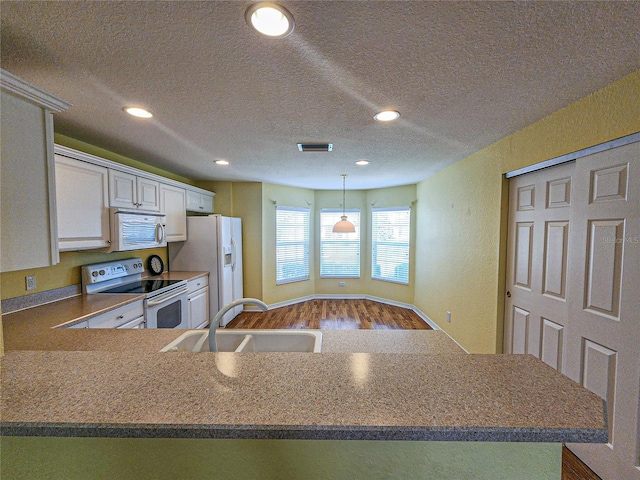 kitchen featuring wood-type flooring, sink, white cabinetry, kitchen peninsula, and white appliances