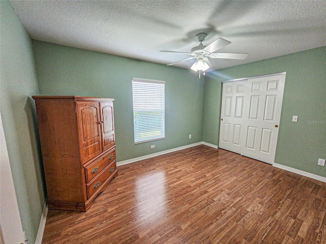 unfurnished bedroom featuring ceiling fan, dark wood-type flooring, and a textured ceiling