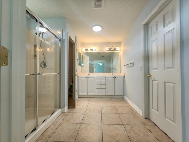 bathroom with a textured ceiling, vanity, tile patterned floors, and a shower with shower door