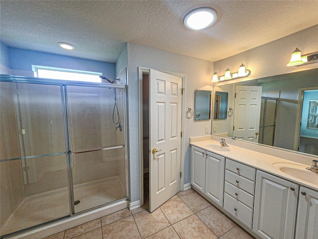 bathroom featuring a shower with shower door, vanity, and a textured ceiling