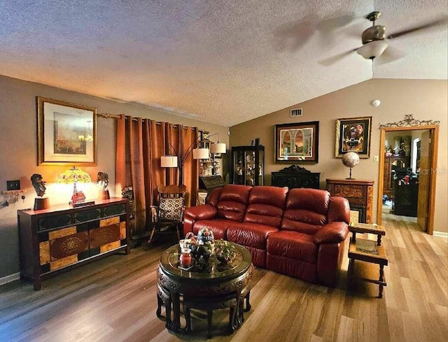 living room with wood-type flooring, a textured ceiling, and vaulted ceiling