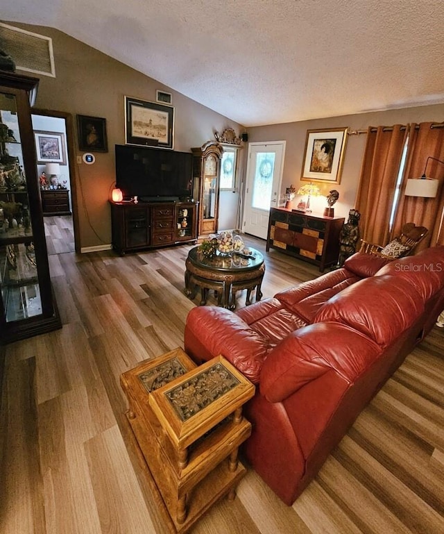 living room with wood-type flooring, a textured ceiling, and lofted ceiling