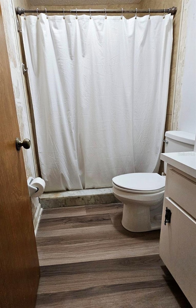 bathroom with hardwood / wood-style floors, vanity, curtained shower, and toilet