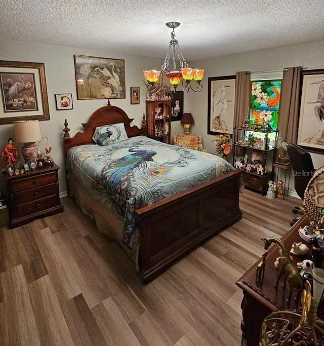 bedroom with a notable chandelier, wood-type flooring, and a textured ceiling