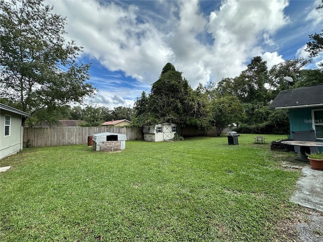 view of yard with an outdoor structure, a fenced backyard, and a shed