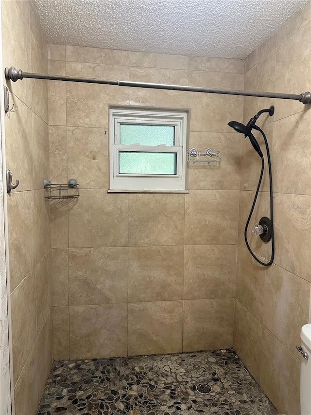 bathroom with tiled shower, a textured ceiling, and toilet