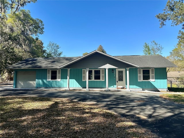 ranch-style house featuring a garage, driveway, and fence