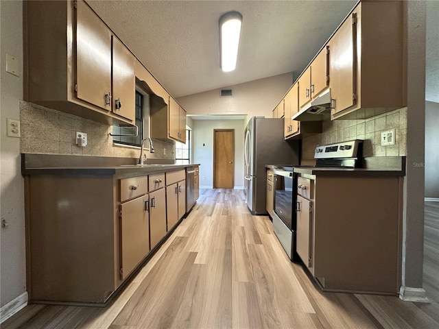 kitchen with visible vents, lofted ceiling, a sink, under cabinet range hood, and appliances with stainless steel finishes