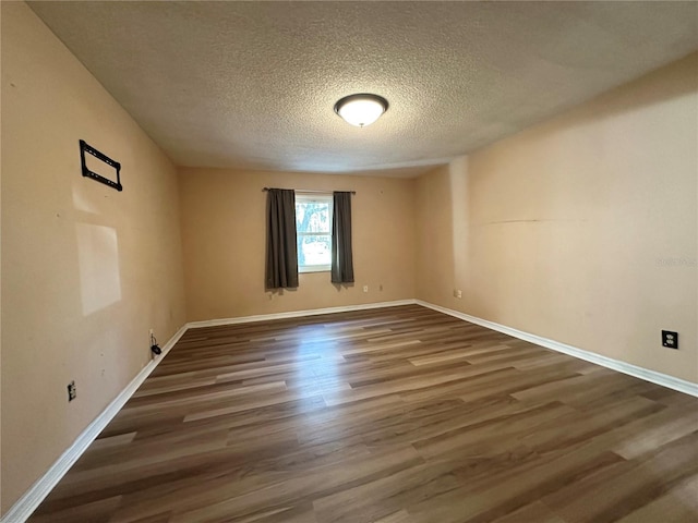 empty room with wood finished floors, baseboards, and a textured ceiling