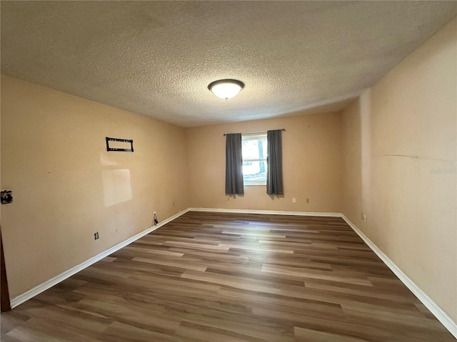 spare room featuring wood finished floors, baseboards, and a textured ceiling