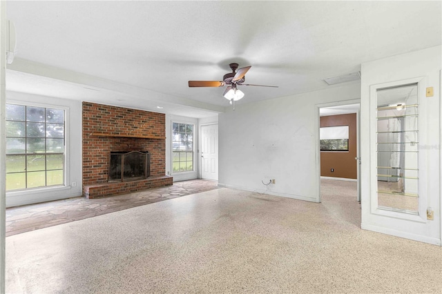 unfurnished living room with ceiling fan, a fireplace, and a wealth of natural light