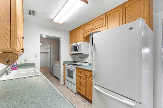 kitchen featuring sink, white appliances, and a textured ceiling