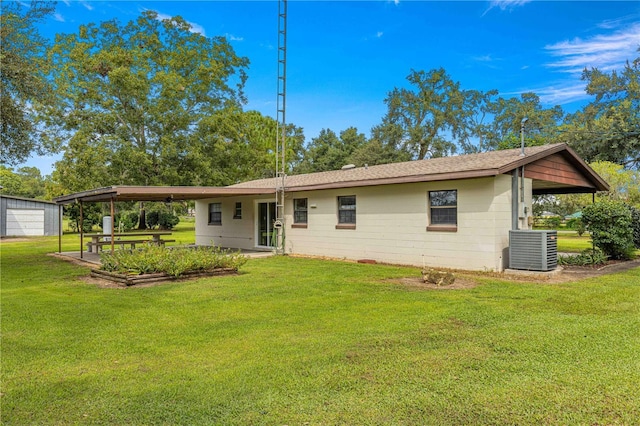 rear view of property with central AC unit and a yard