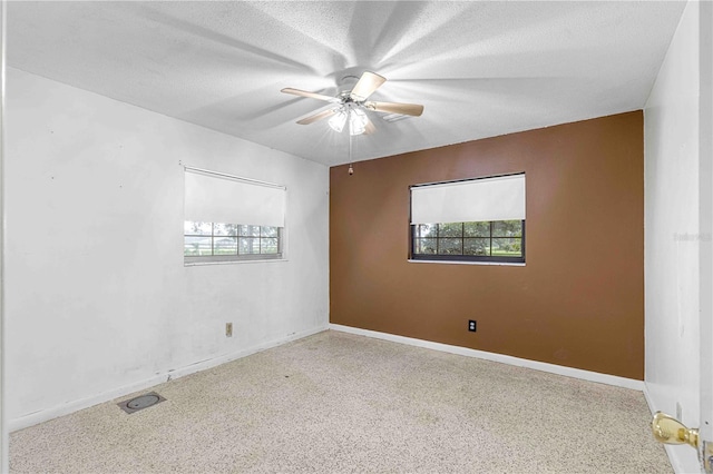 empty room with ceiling fan, a healthy amount of sunlight, and a textured ceiling