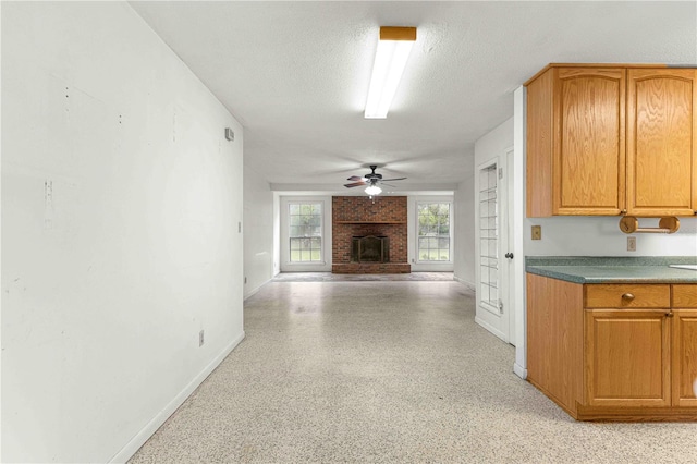 kitchen featuring a brick fireplace, a textured ceiling, and ceiling fan