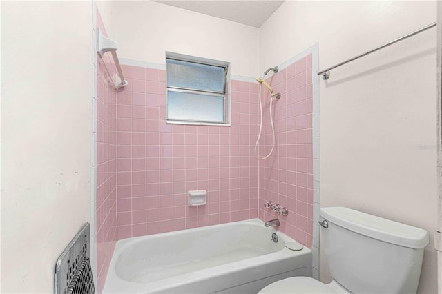 bathroom with tiled shower / bath combo, a textured ceiling, and toilet