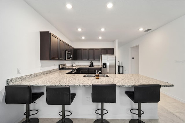 kitchen featuring a breakfast bar, dark brown cabinets, sink, kitchen peninsula, and stainless steel appliances