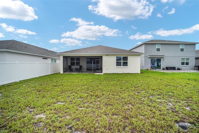 rear view of house with a yard, a sunroom, and a patio area