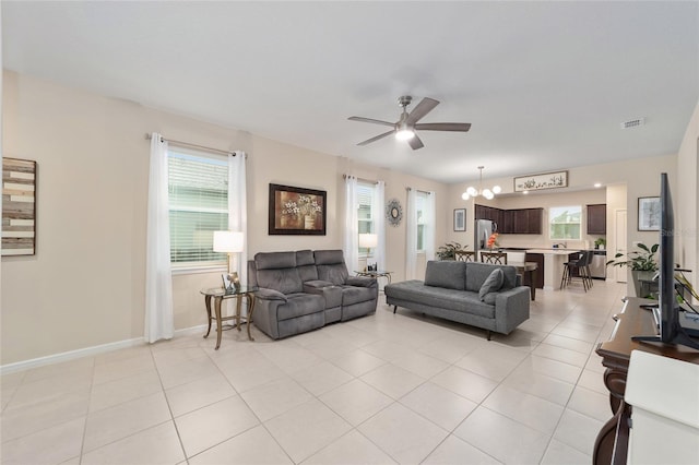 tiled living room with ceiling fan with notable chandelier