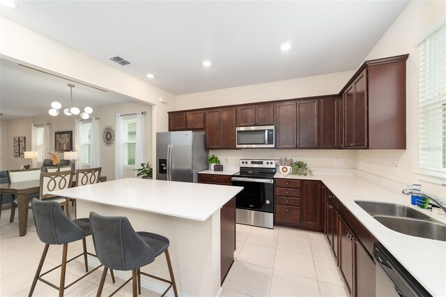 kitchen with sink, decorative light fixtures, a chandelier, appliances with stainless steel finishes, and a kitchen breakfast bar