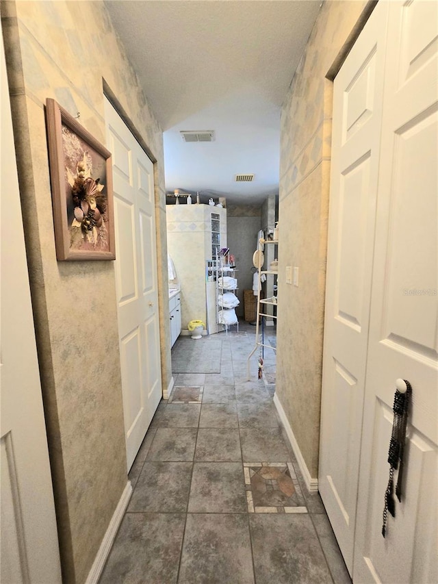 hallway with dark tile patterned floors and a textured ceiling