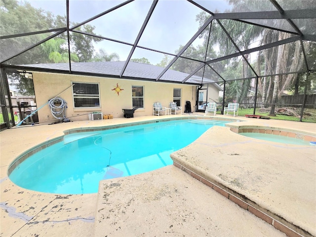 view of pool with glass enclosure, an in ground hot tub, and a patio