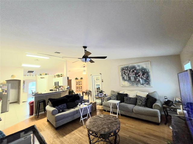 living room with a textured ceiling, ceiling fan, wood-type flooring, and vaulted ceiling