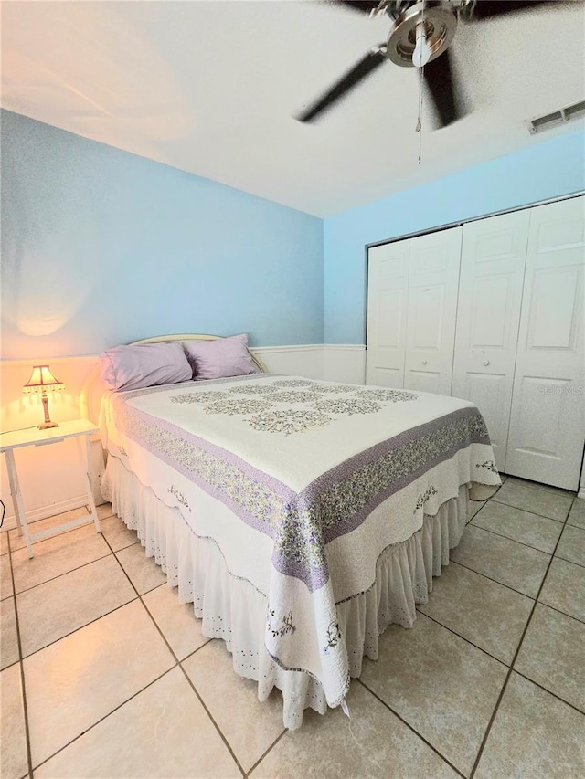 tiled bedroom featuring ceiling fan and a closet