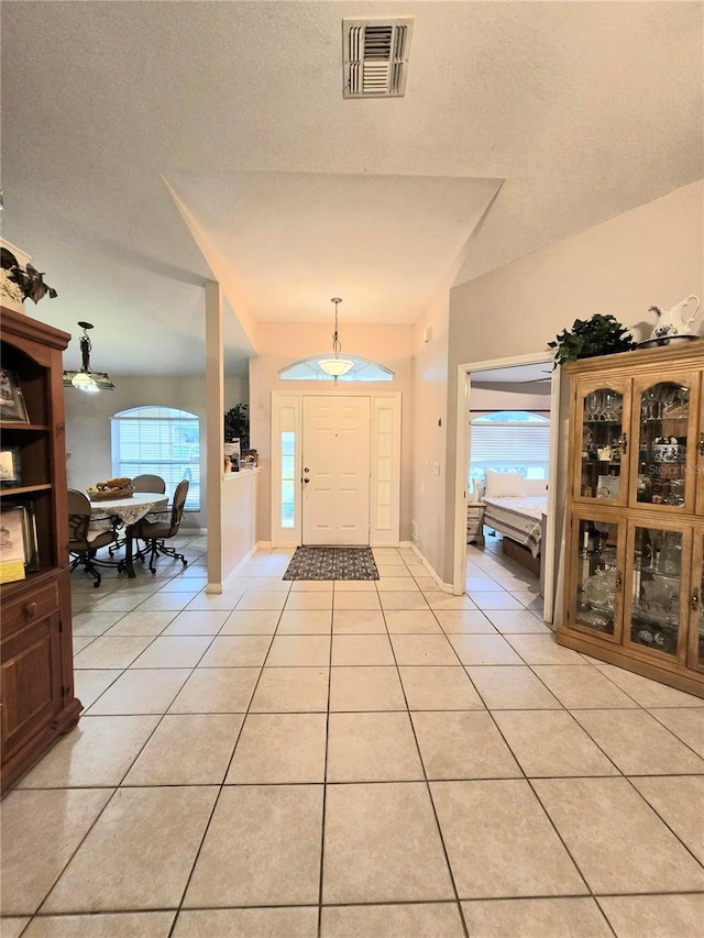 foyer entrance featuring visible vents, a textured ceiling, baseboards, and light tile patterned floors