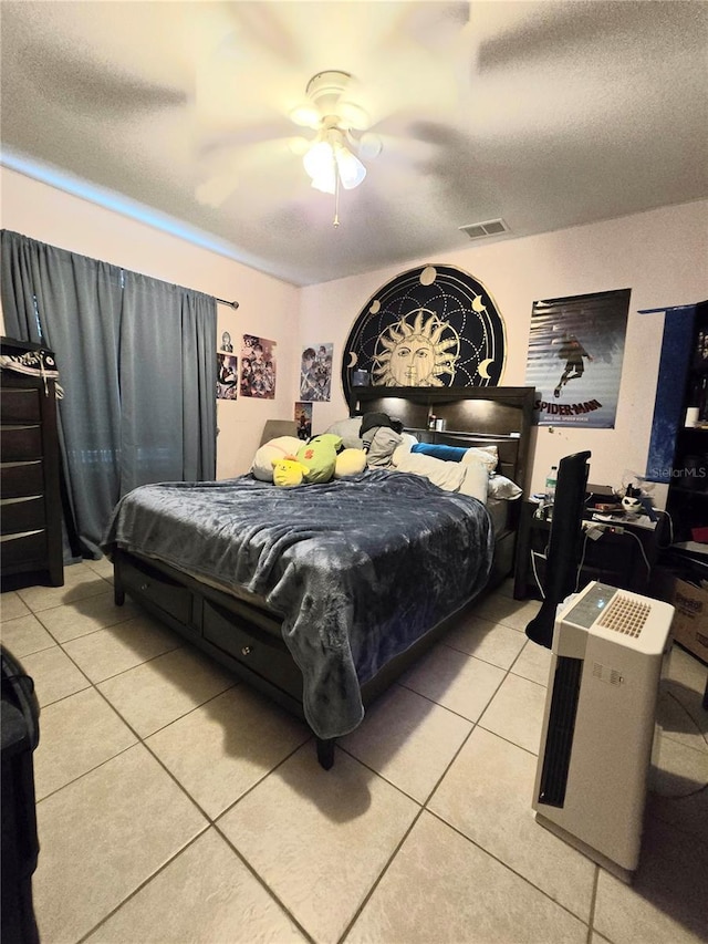 bedroom with ceiling fan, light tile patterned flooring, and a textured ceiling