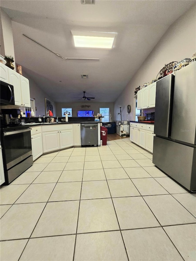 kitchen with white cabinetry, ceiling fan, vaulted ceiling, light tile patterned flooring, and appliances with stainless steel finishes