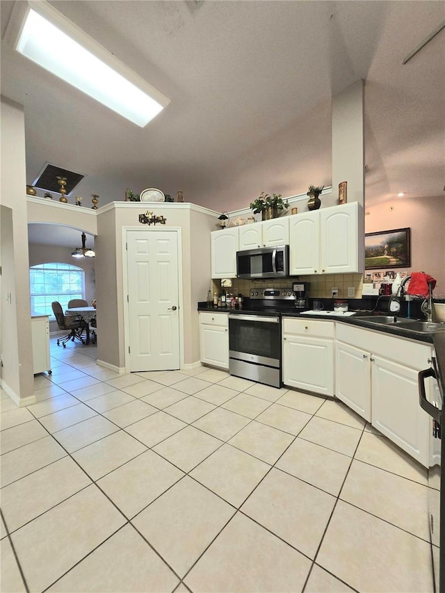 kitchen with appliances with stainless steel finishes, light tile patterned floors, tasteful backsplash, and white cabinetry